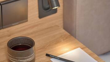 A modern, minimalist room with a wooden panel wall, a black switch, a small cup, a pencil, and a piece of paper with the word "AMAYA" written on it.