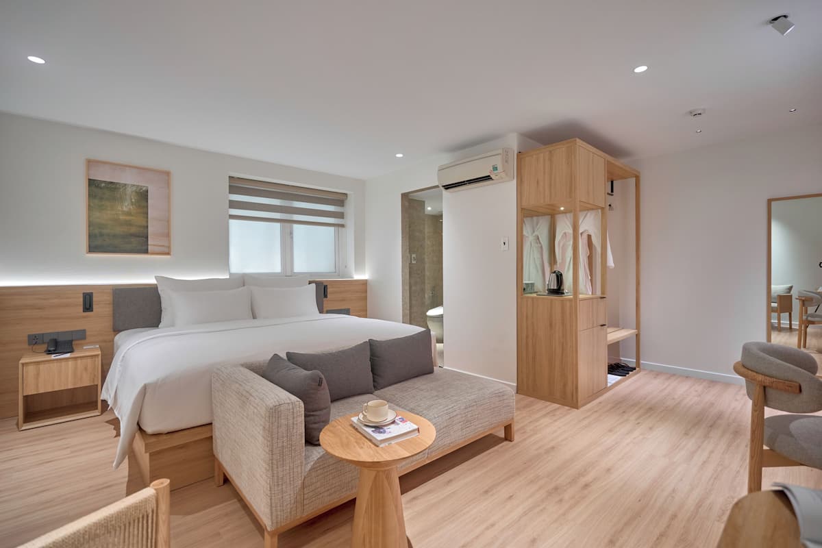 A modern bedroom with a large bed, a sofa, a small table, and a wardrobe.