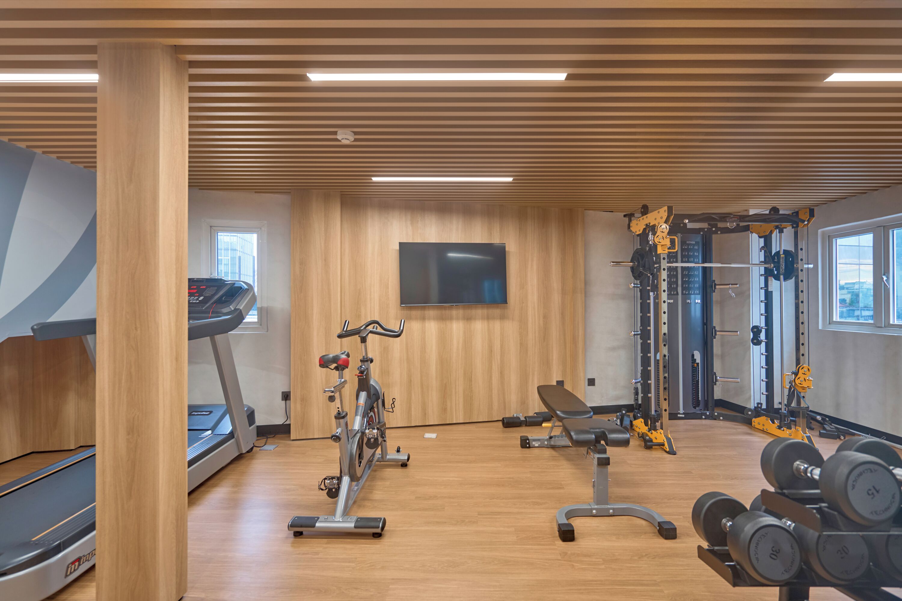 Una palestra con tapis roulant, ellittiche, una panca e attrezzature per sollevamento pesi.