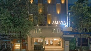 A modern hotel with a prominent 'AMAYA' sign, featuring a multi-story structure with illuminated vertical lines and a well-lit entrance. - Amaya Saigon Boutique Hotel (Ho Chi Minh City)