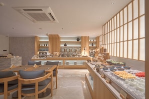 A modern dining area with wooden furniture and a buffet counter with various food items. - Amaya Saigon Boutique Hotel (Ho Chi Minh City)