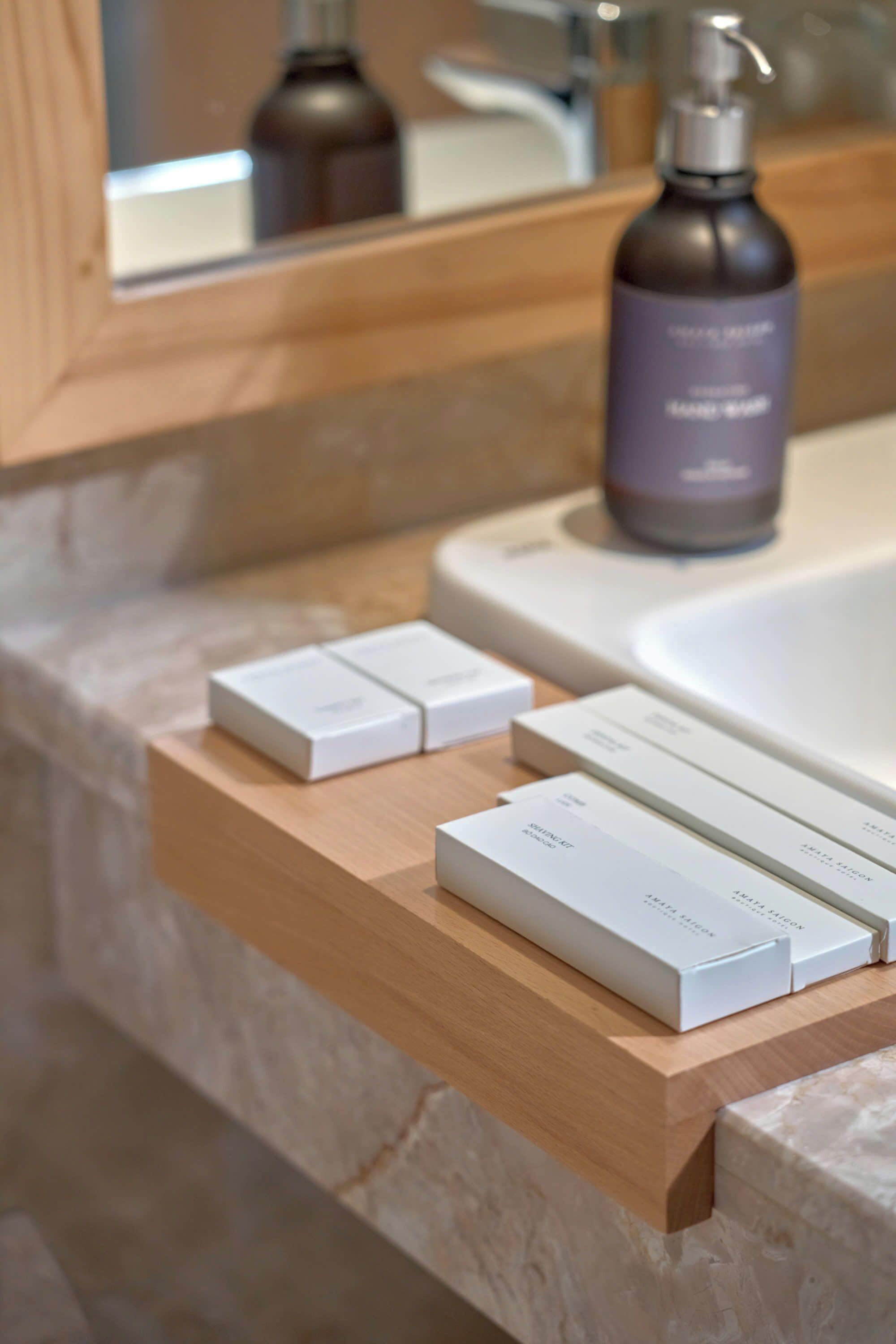 A bathroom with a marble countertop, a wooden shelf with boxes, and a bottle of hand soap.