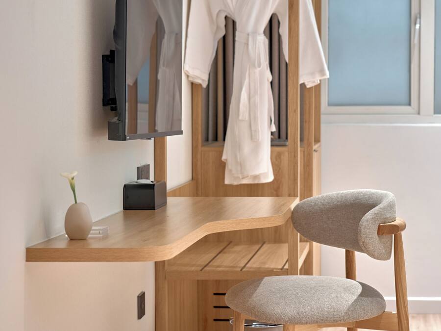 A modern bathroom with a wooden vanity, a mirror, and a towel rack.
