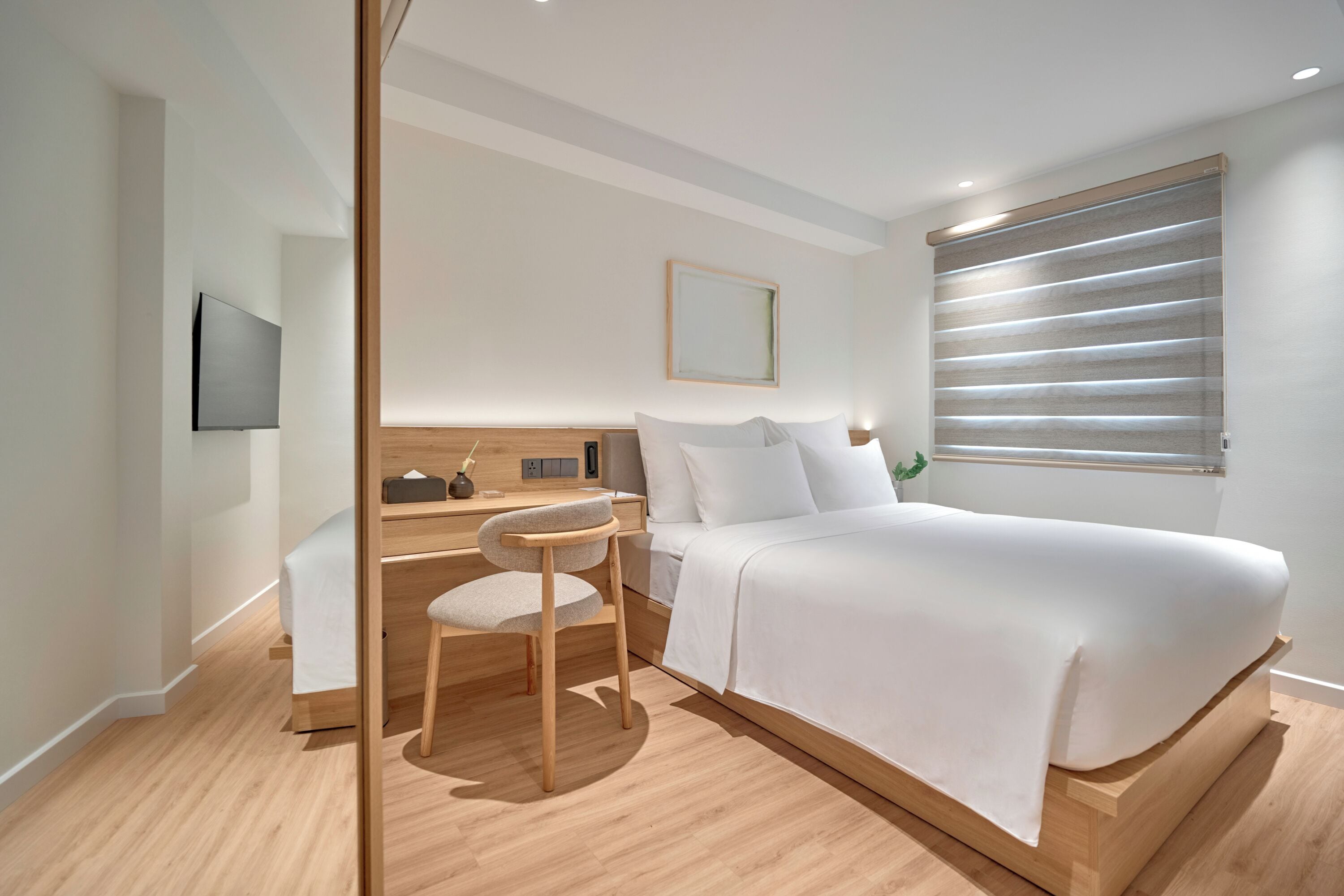 Een moderne slaapkamer met een bed, een bureau en een stoel.