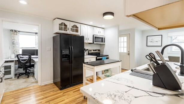 A modern kitchen with white cabinets, a black refrigerator, a microwave, and a marble countertop. - Charming Coastal Retreat w Community Beach Dog-Friendly & Mins to Downtown Annapolis (Annapolis)
