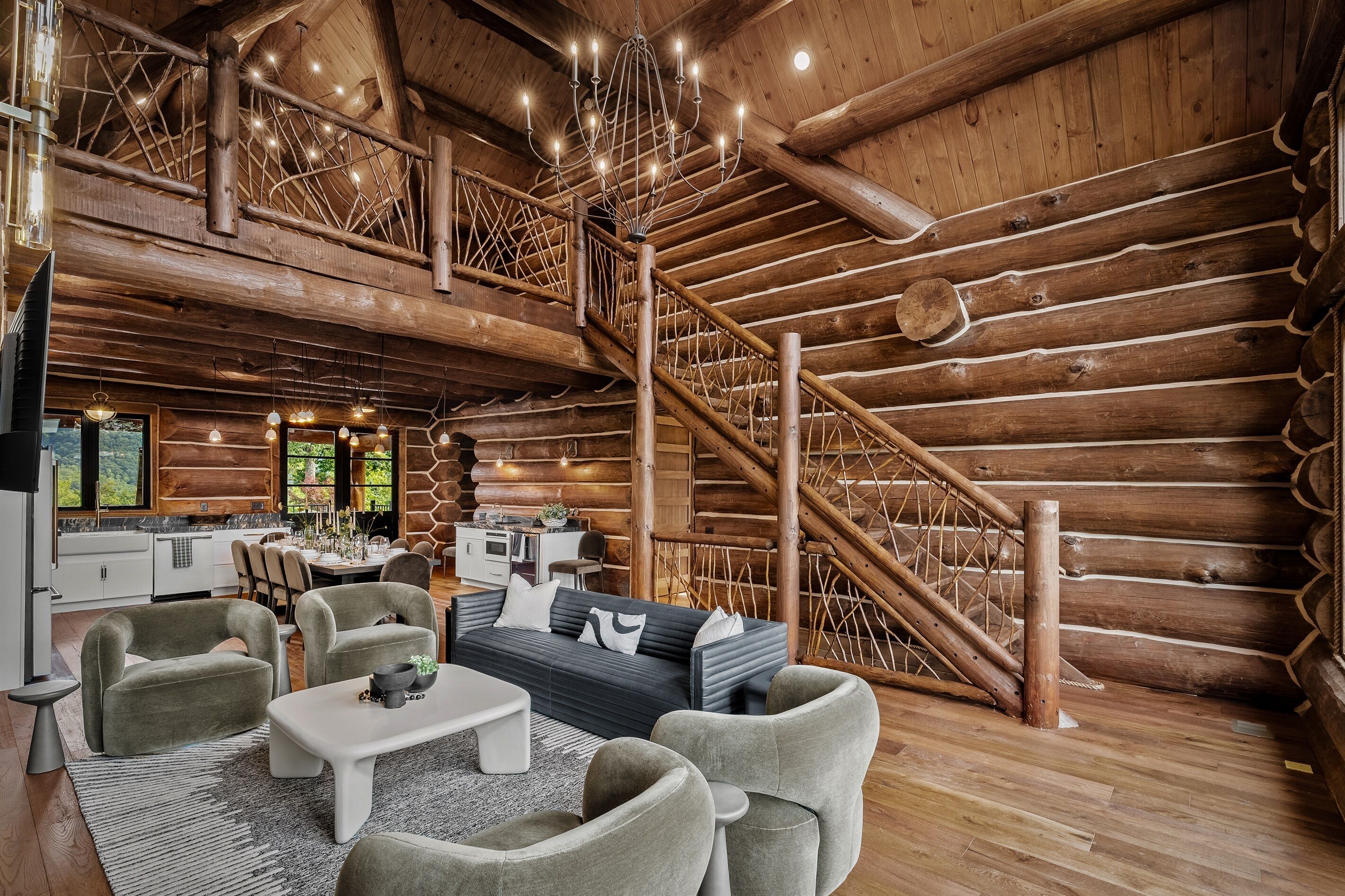 A log cabin interior with a dining area, sofa, and staircase.