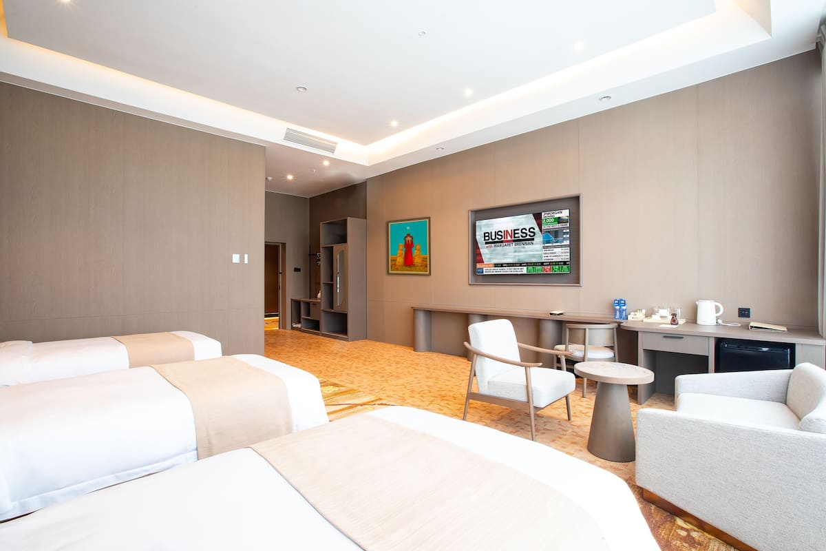 A hotel room with two beds, a desk, a chair, and a small table.