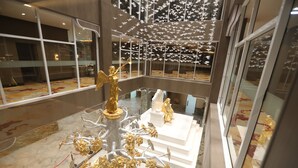 A modern interior with a central golden tree sculpture, white steps, and a ceiling with hanging white objects. - Khubilai Hotel Ulaanbaatar (Ulaanbaatar)