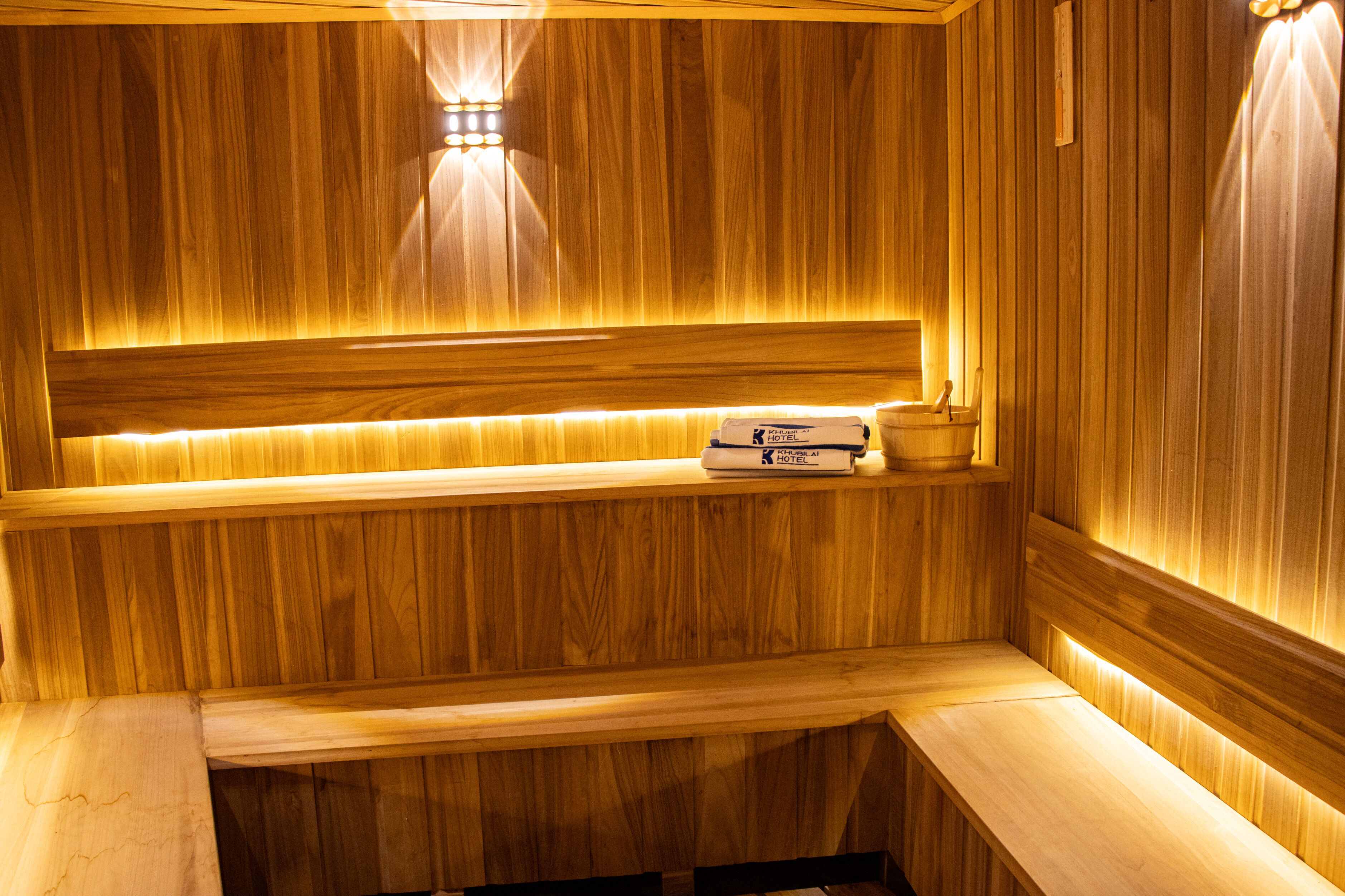 Una sauna de madera con un banco, un estante con una toalla y un perchero.