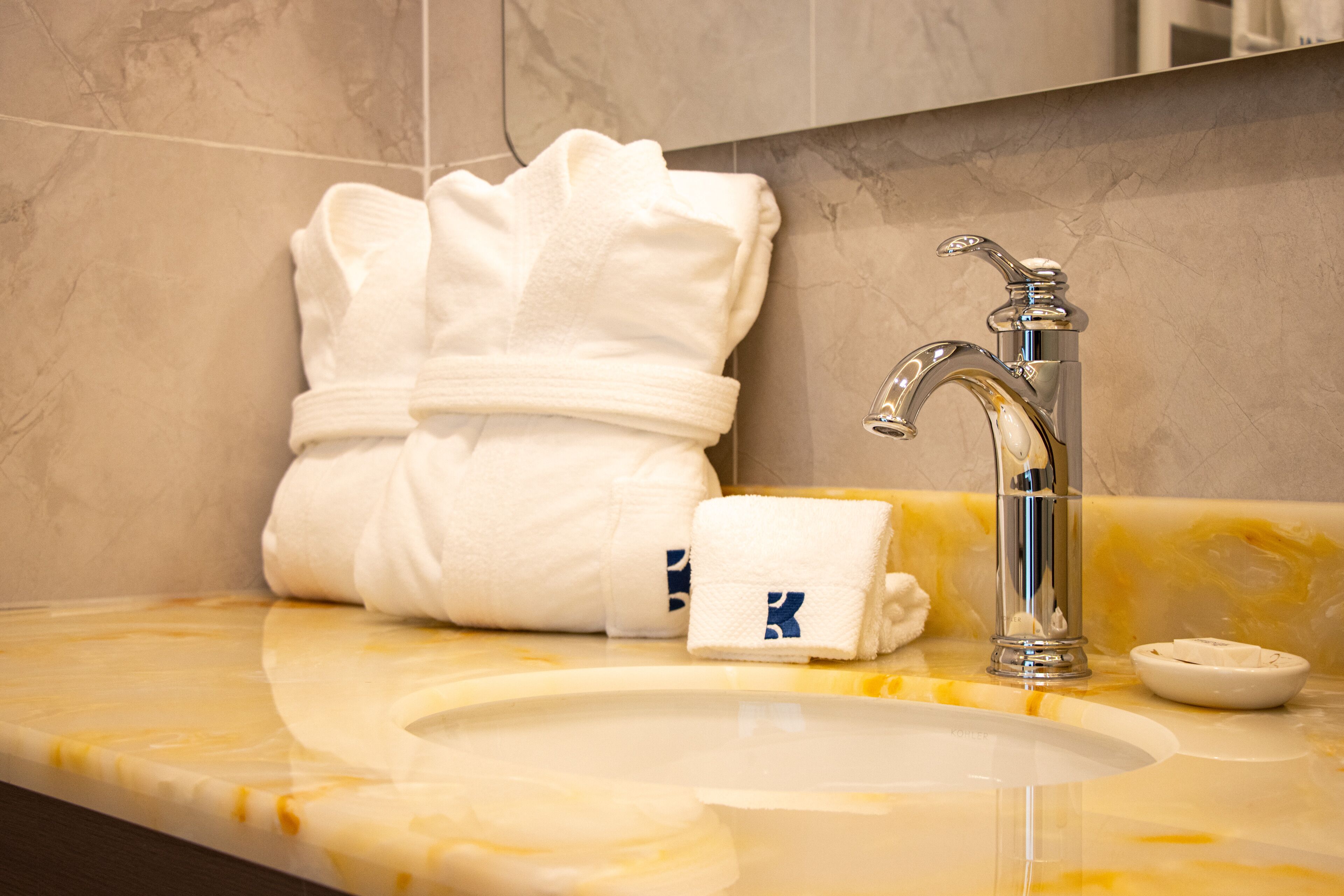 A bathroom with a marble sink, a chrome faucet, and neatly folded towels.