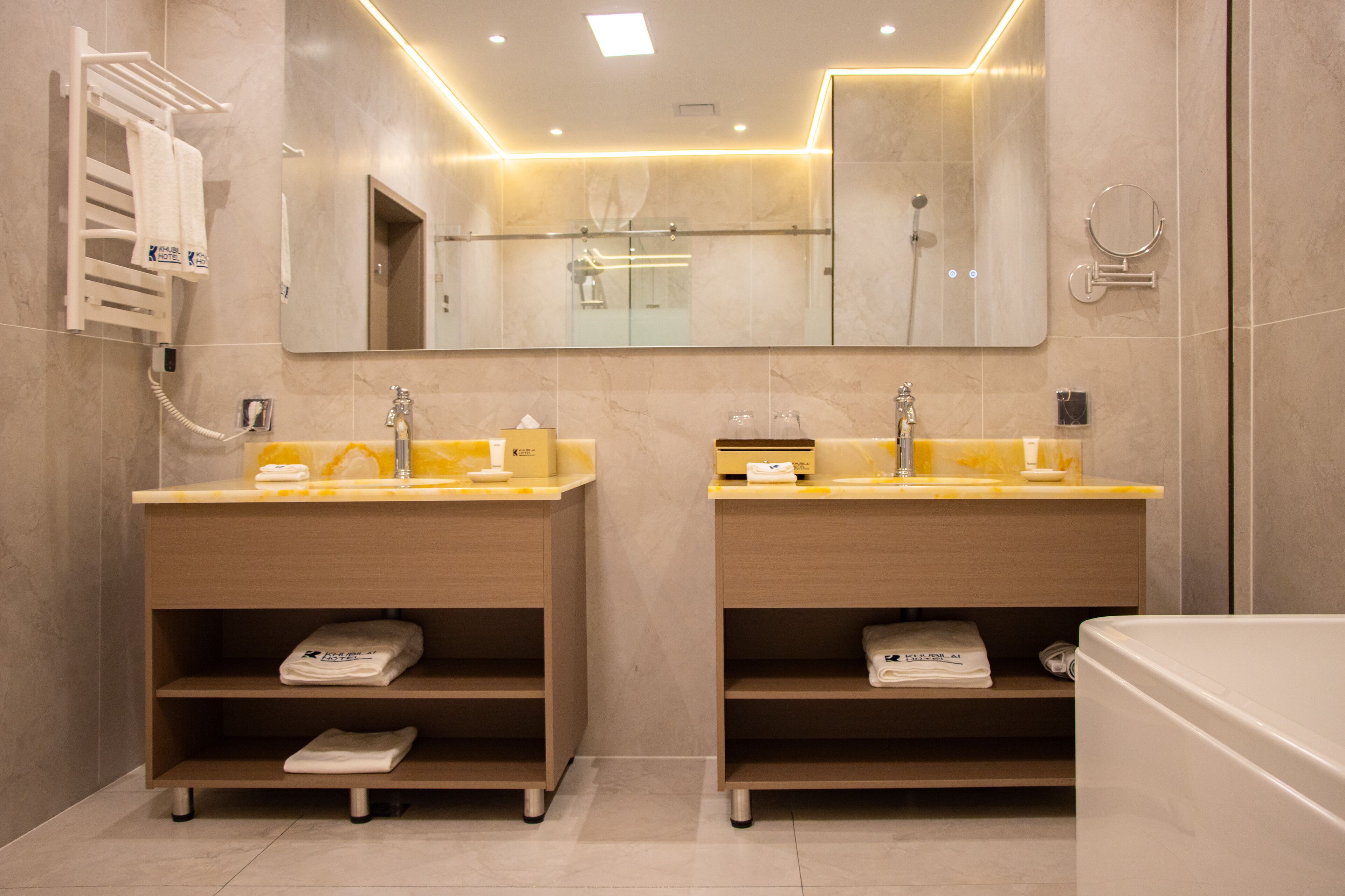 A modern bathroom with two sinks, a large mirror, and a shower area.