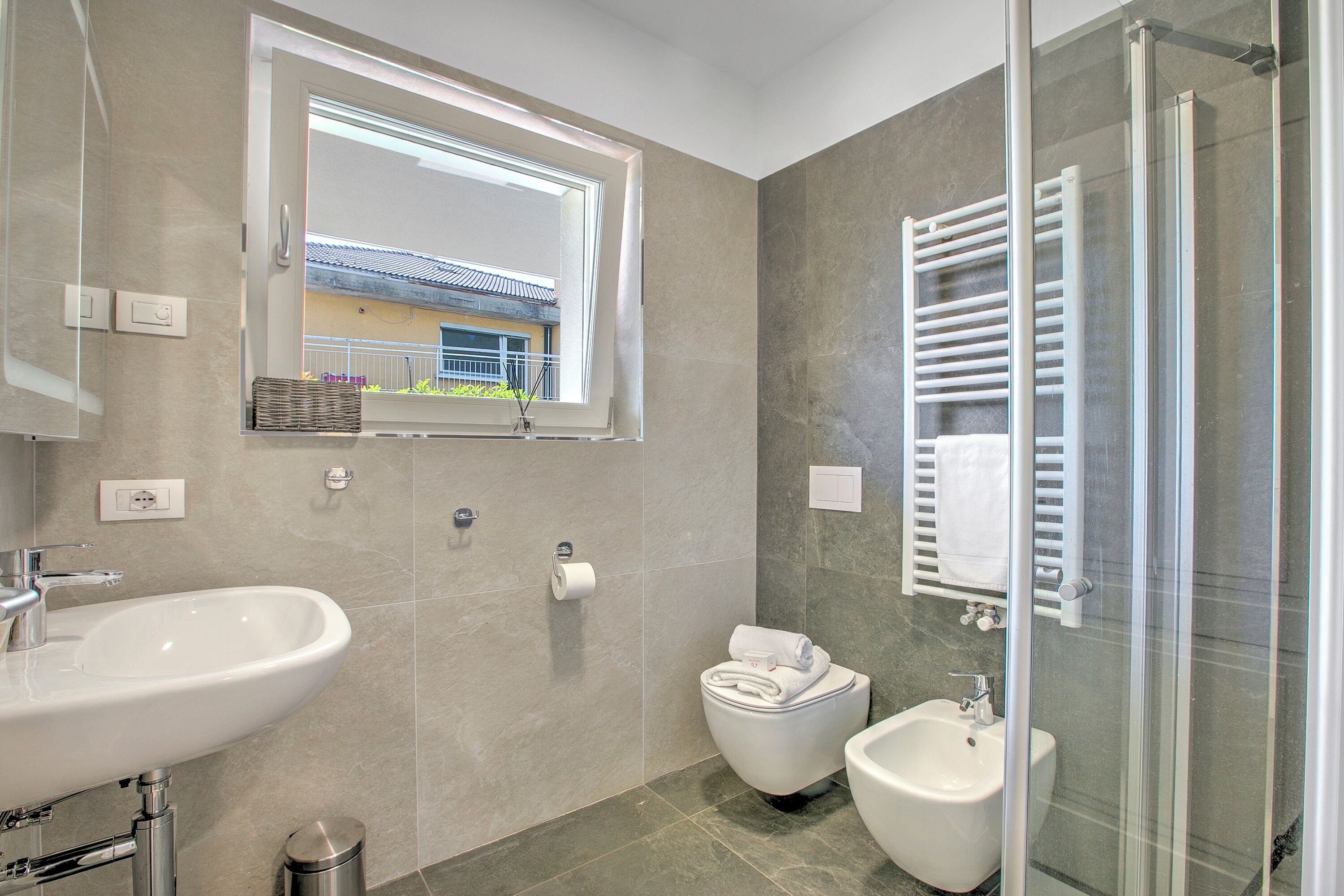 Un baño moderno con lavamanos, bidé y cabina de ducha de vidrio.