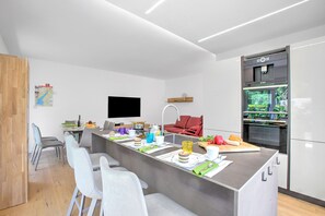 Une cuisine moderne dotée d’un îlot central, d’un four encastré et d’un téléviseur à écran plat.