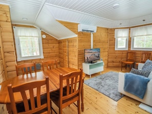 Ein gemütliches Blockhauss-Interieur mit Essbereich, einer Couch und einem Fernseher.
