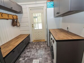 Une cuisine compacte équipée d’un lave-linge, d’un plan de travail en bois et d’une porte avec fenêtre.