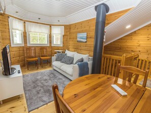L’intérieur d’un chalet accueillant, avec un canapé, des fauteuils, une table à manger et une cheminée.