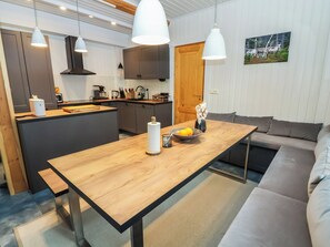 Une cuisine moderne dotée d’un îlot central, de luminaires suspendus et d’un coin repas avec un canapé.