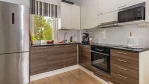 A modern kitchen with a stainless steel refrigerator, a built-in oven, and a microwave.