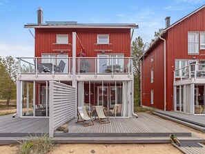 A modern red two-story house with a balcony, glass doors, and a wooden deck. - Hailuodon villa merituuli by Interhome (Hailuoto)