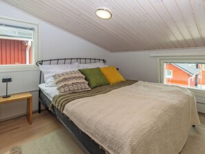 A bedroom with a bed, pillows, a bedside table, a window, and a ceiling light. - Hailuodon villa merituuli by Interhome (Hailuoto)