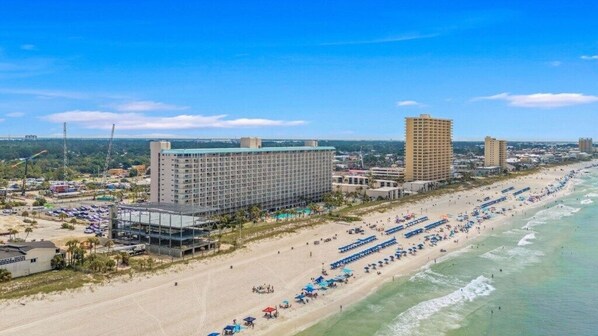 Un hôtel situé sur la côte, avec plusieurs étages, donnant sur la plage et disposant d’un parking.