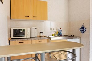 Una cocina con armarios de madera, microondas, cafetera, fregadero y lavavajillas.