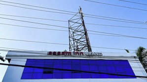 A building with a sign reading "assam inn grand" and a tall electrical tower in the background. - Assam Inn Grand  (Guwahati)