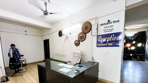 A reception desk with a sign for 'assam inn grand khanamutti guwahati' and a 'checkout time: 11AM' sign. - Assam Inn Grand  (Guwahati)