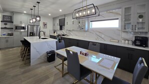 Una cocina moderna con encimera de mármol, electrodomésticos de acero inoxidable y una isla central con taburetes de bar.