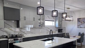Una cocina moderna con una isla grande, armarios negros e iluminación colgante.