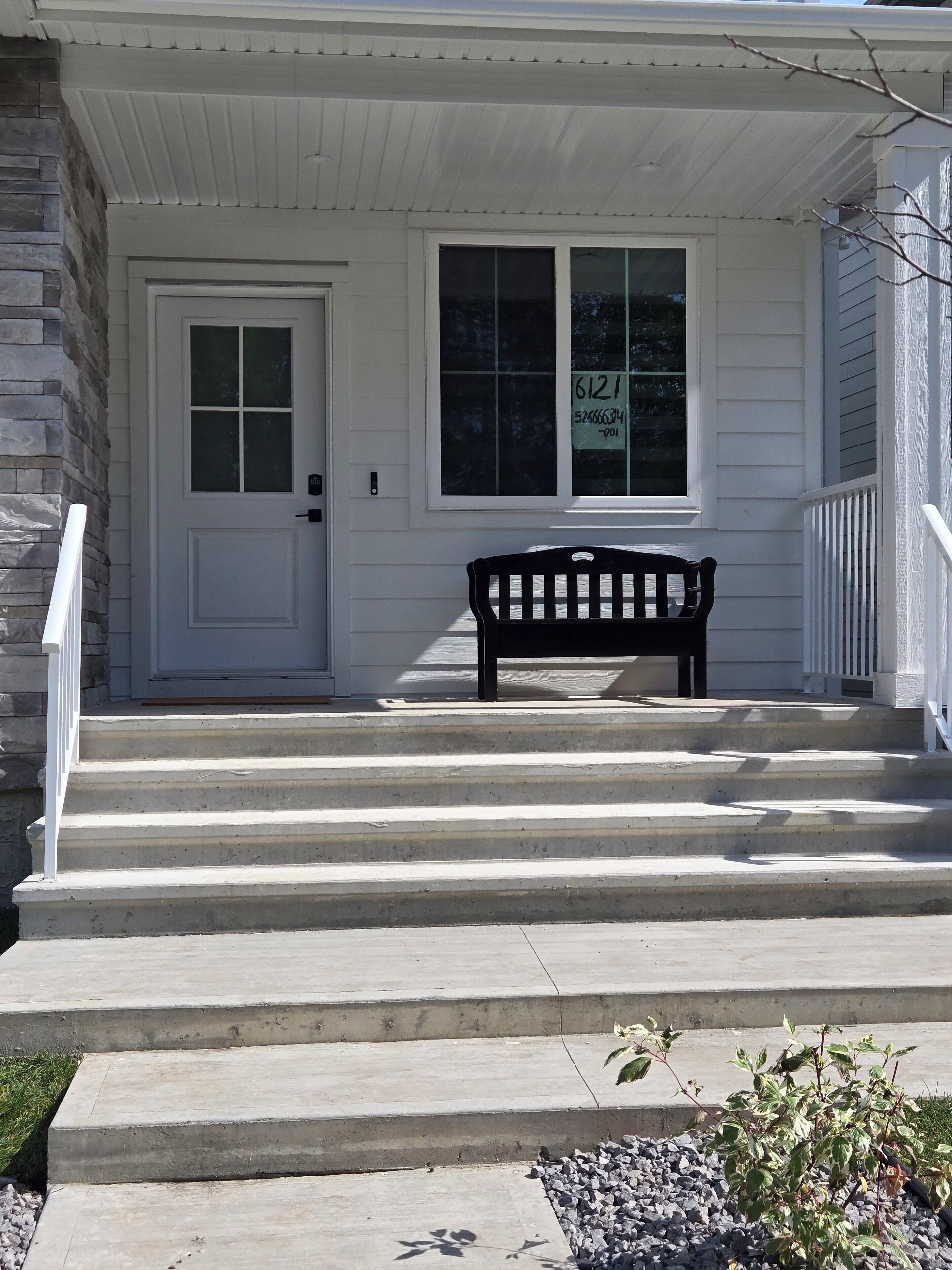 A front porch with a bench, a door, and a window.