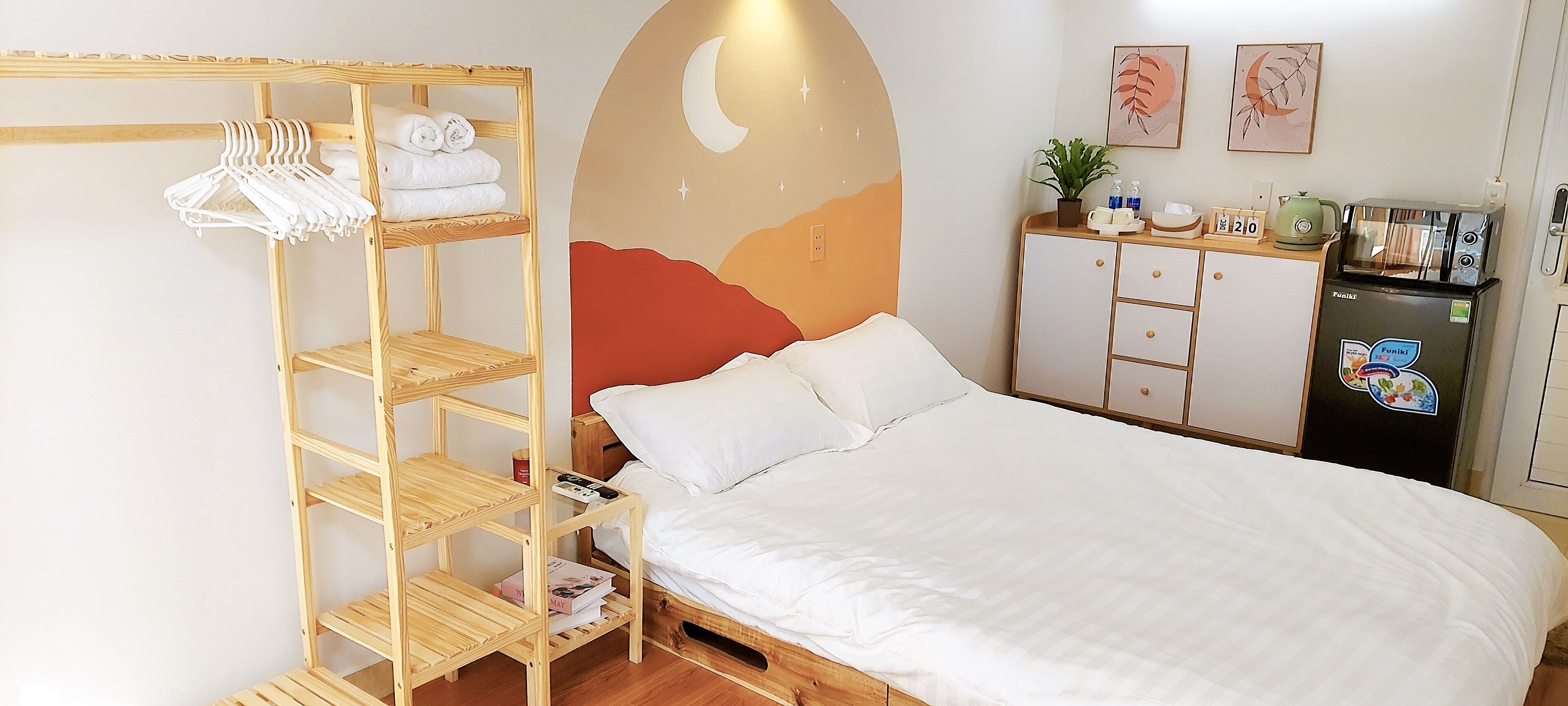 Ein ordentlich eingerichtetes Hotelzimmer mit einem Bett, einem Holzschrank, einer Küchenzeile und einer Wand mit einem Halbmond-Design.