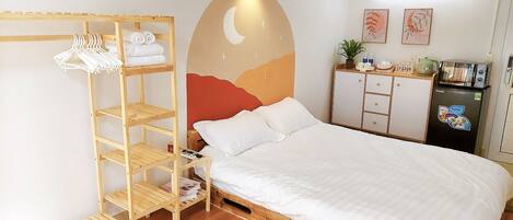 Ein ordentlich eingerichtetes Hotelzimmer mit einem Bett, einem Holzschrank, einer Küchenzeile und einer Wand mit einem Halbmond-Design.