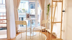 Une pièce avec une table ronde, deux chaises, une petite plante et une étagère en bois.