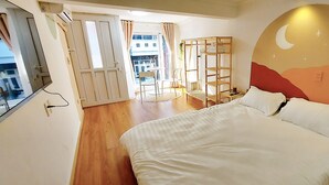 Une chambre à coucher avec un lit, un plancher en bois, une fenêtre et un mur orné d’un motif en forme de croissant de lune.