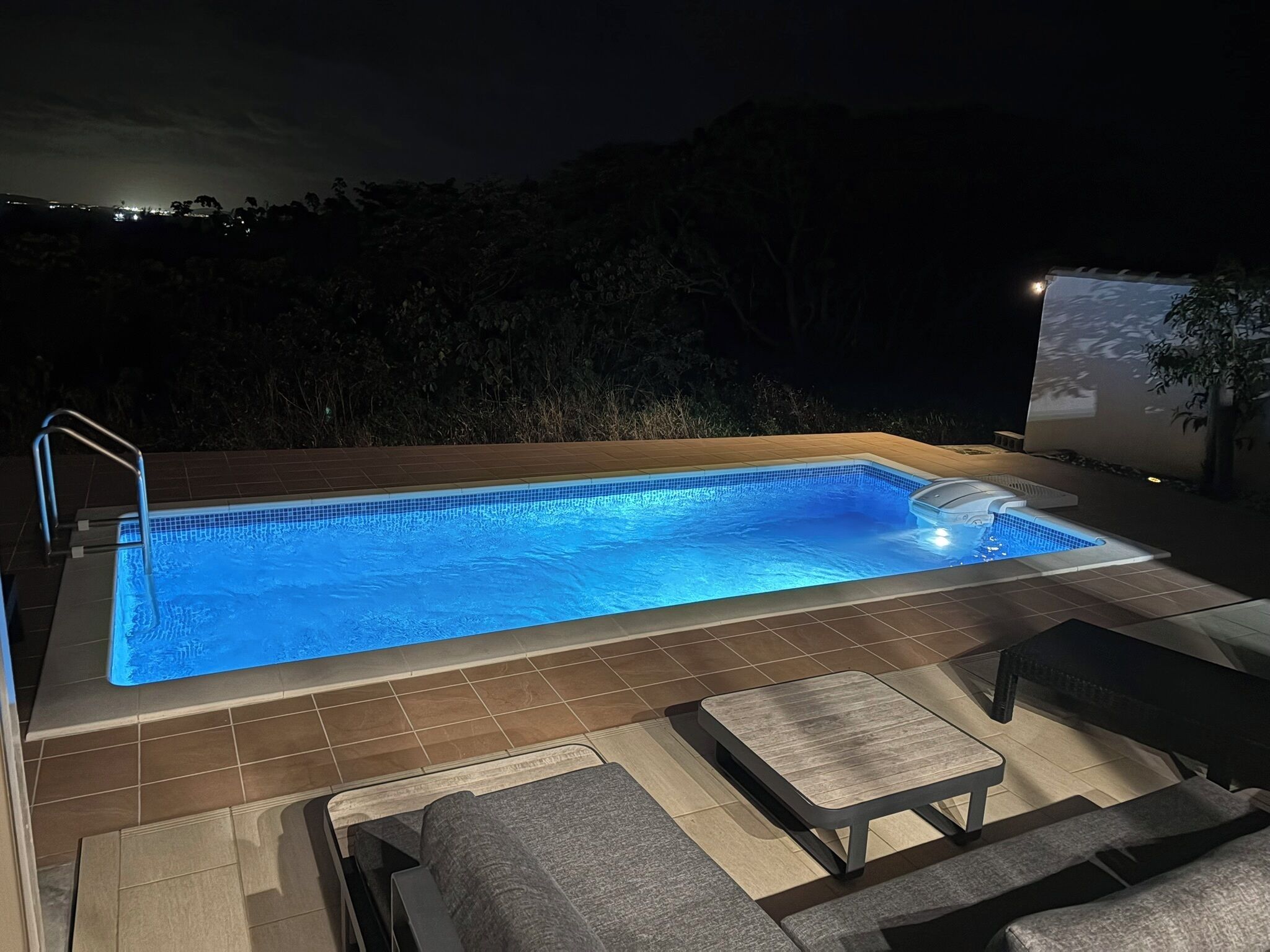 Ein Schwimmbecken mit gefliestem Deck und Liegestühlen.