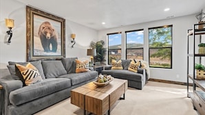 A living room with two grey sofas, a wooden coffee table, and a large bear picture on the wall. - Deer Valley Grand Residence 4BR 10 min from skiing (Hideout)