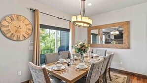 A dining room with a wooden table set for six, a large wall clock, and a mirror above the table. - Deer Valley Grand Residence 4BR 10 min from skiing (Hideout)