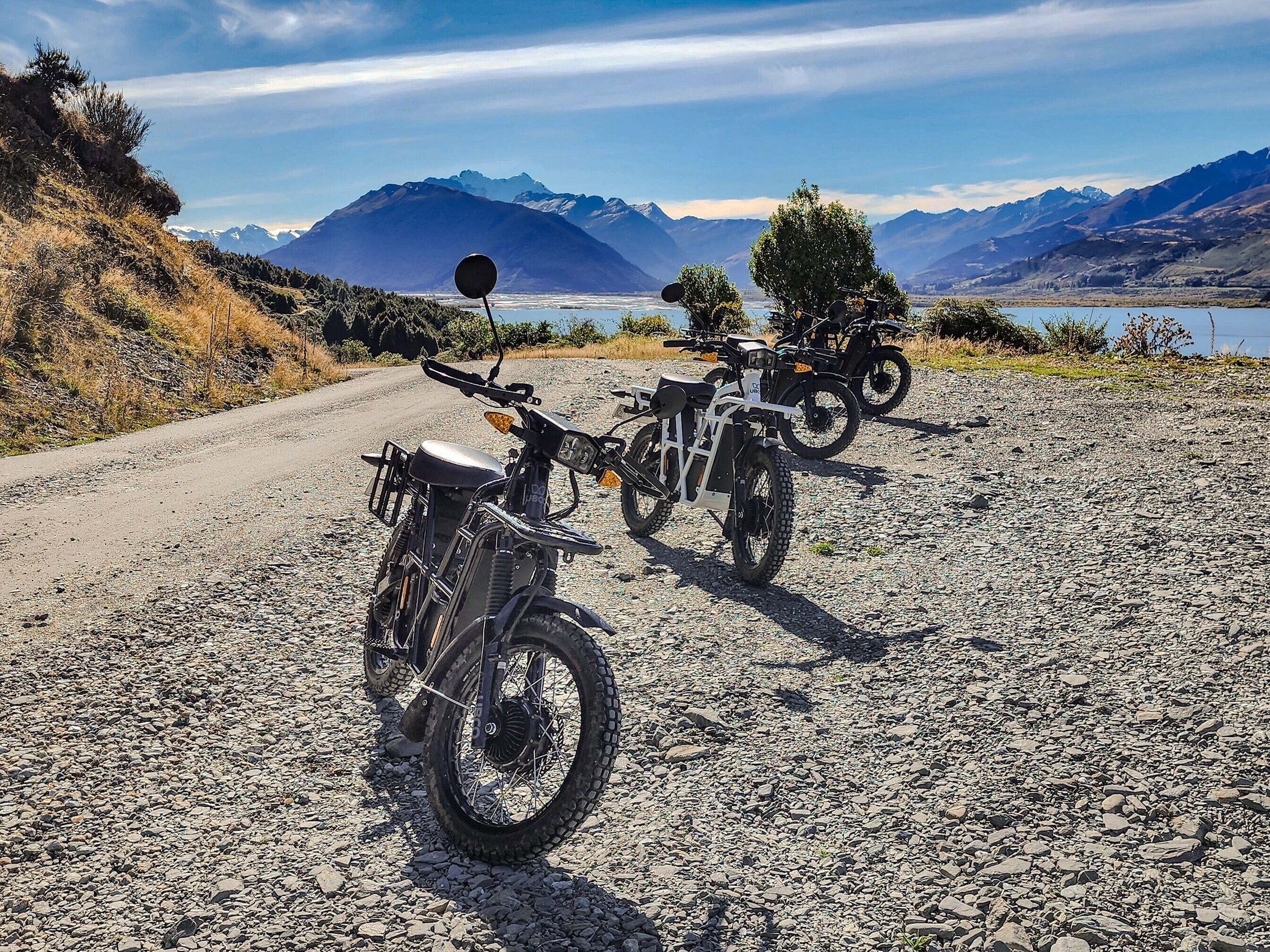 A gravel road with three off-road motorcycles parked.