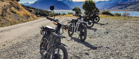 A gravel road with three off-road motorcycles parked.