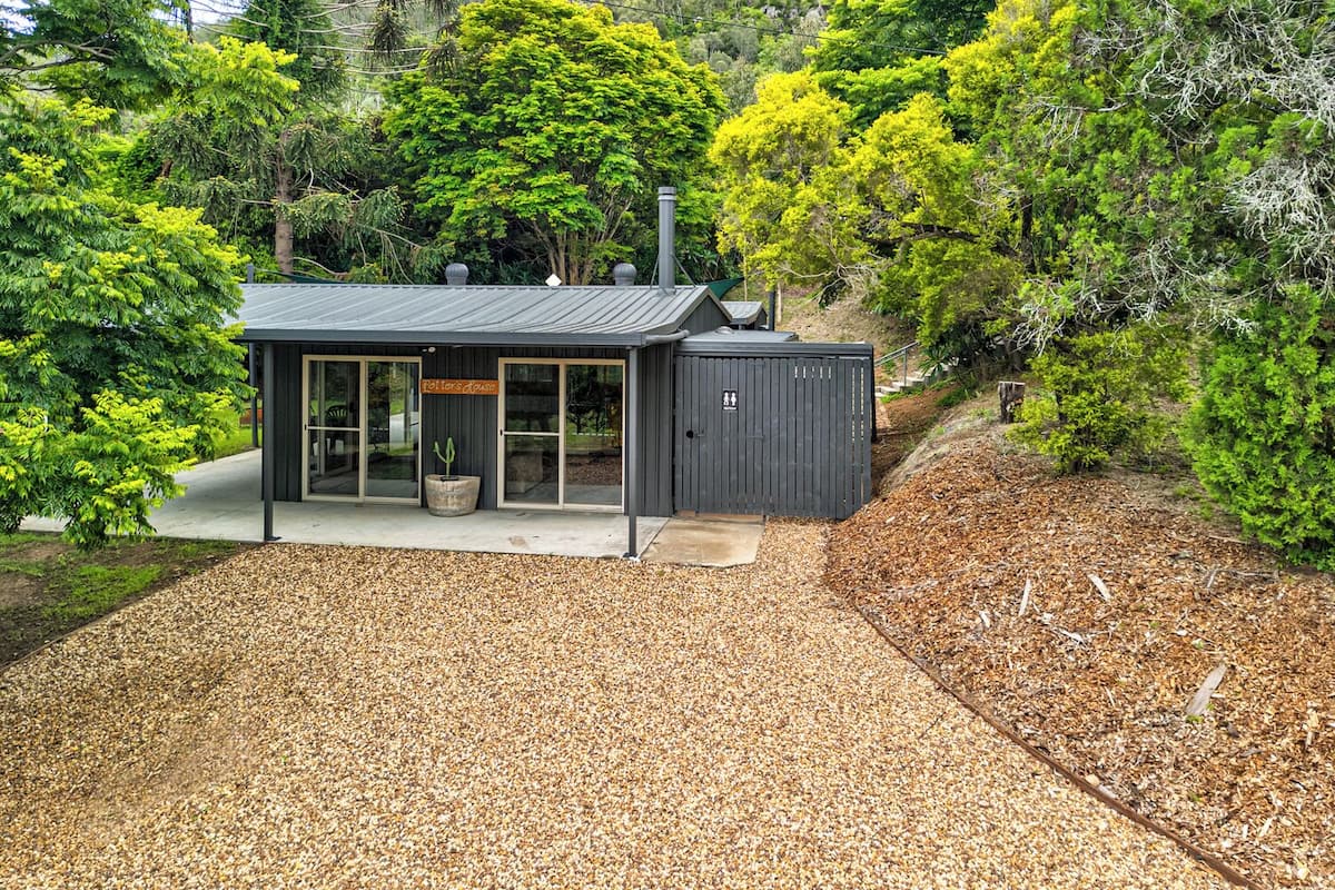 A modern, dark-colored building with a glass entrance and a small garden area in front.