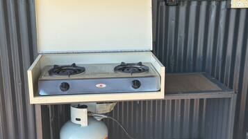 Een draagbaar gasfornuis met twee branders, een gasfles en een metalen behuizing.