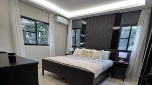 Un dormitorio moderno con una cama grande, una mesita de noche, un aparador y una ventana con cortinas.