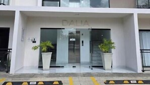 Un edificio de varios pisos con un diseño arquitectónico moderno, que cuenta con amplios ventanales y una entrada central con un letrero.