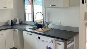 Een moderne keuken met witte kasten, een inbouwvaatwasser, een houten aanrechtblad en een raam met uitzicht op de omgeving.