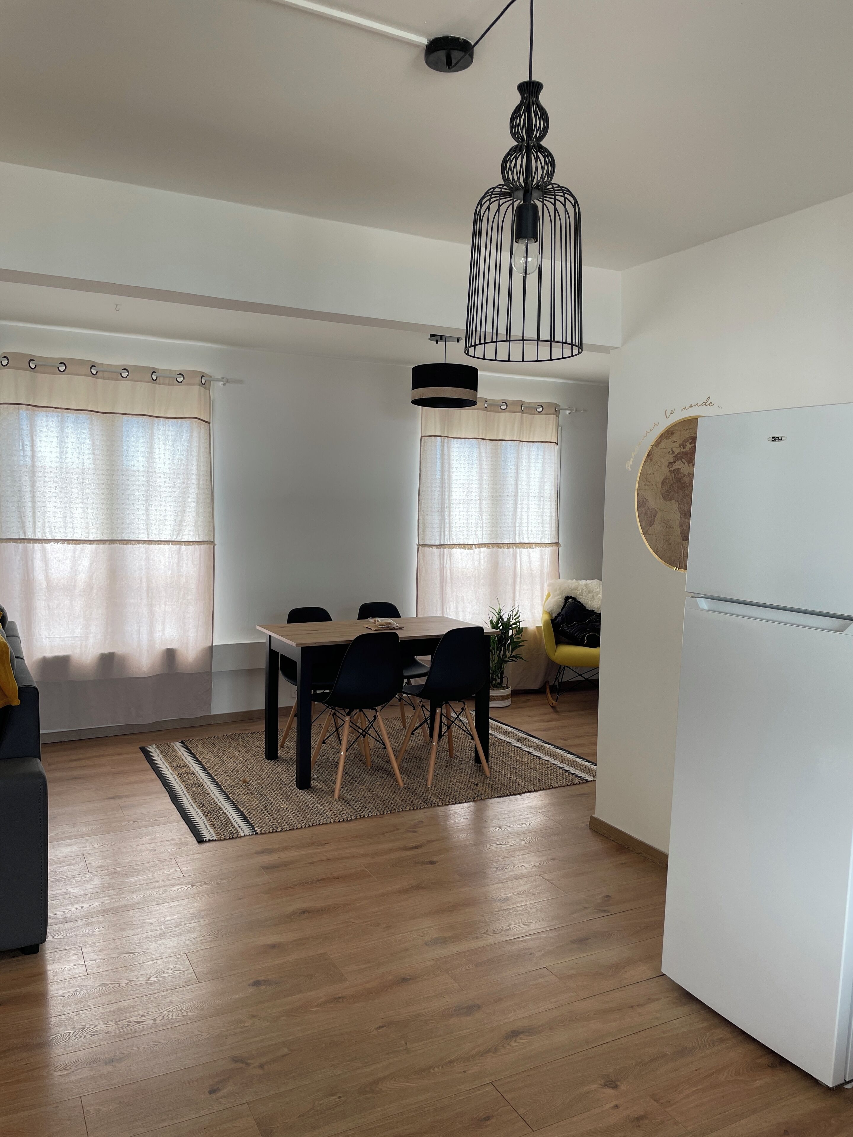 A modern kitchen with a white refrigerator, wooden dining table, and black chairs.