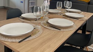 Een eetruimte met een houten tafel voor vier personen, omringd door zwarte stoelen.