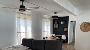 Een moderne slaapkamer met een groot bed, een plafondventilator en een eethoek op de achtergrond.