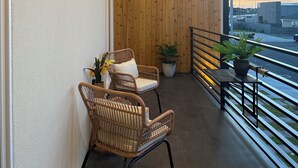 Un balcon avec deux fauteuils en osier, une petite table et un pot de fleurs.