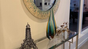 Une console en verre agrémentée d’un miroir décoratif, d’une maquette de la tour Eiffel et d’une maquette de vélo.